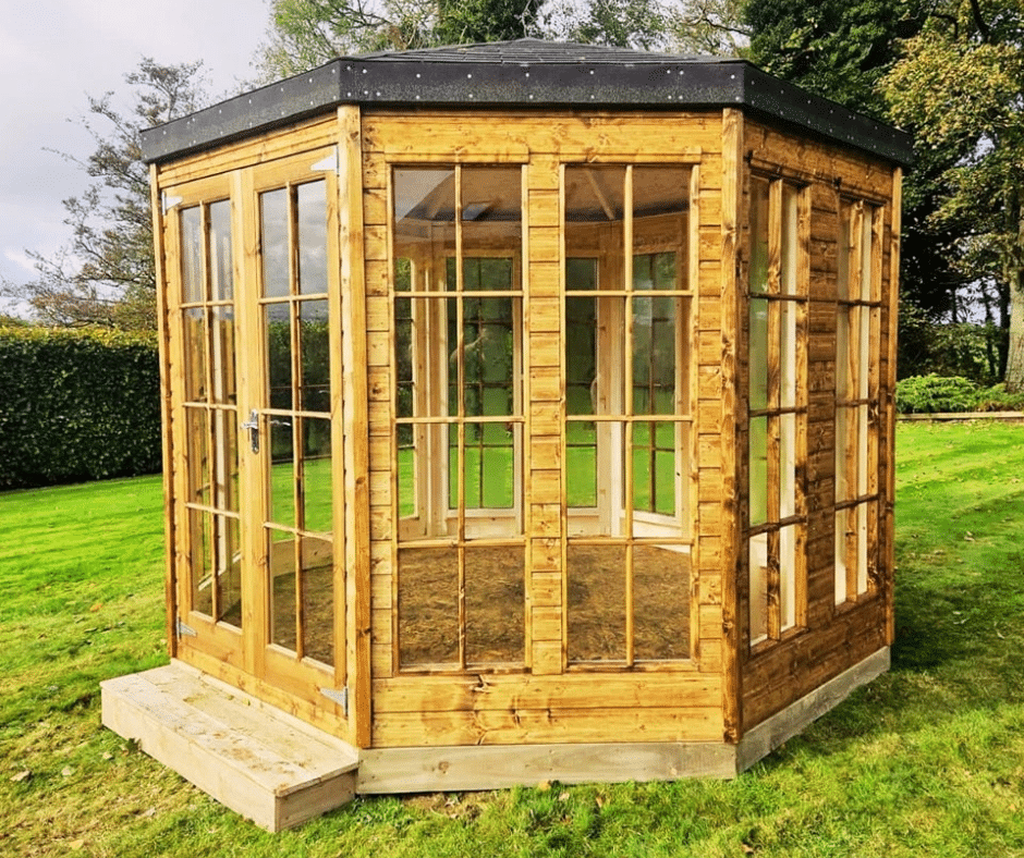 Wooden summerhouse with glass-paneled doors and windows on a grassy lawn.