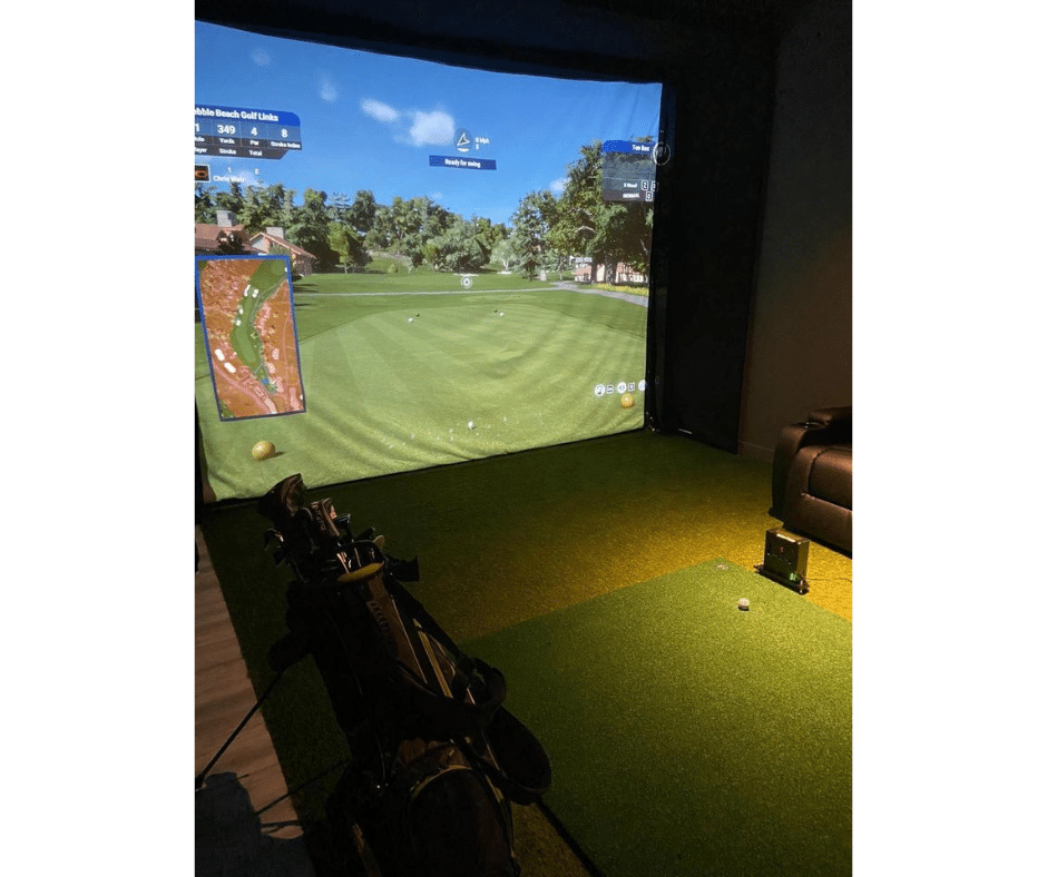 Golf simulator room with projector screen displaying a golf course, green turf, and golf equipment.